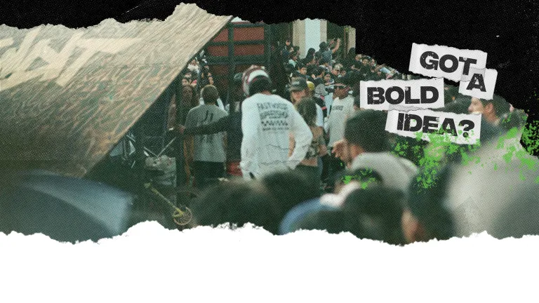 crowd watches skateboarders on a ramp at an event 